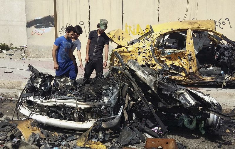 Iraqis inspect the scene after a car bomb explosion in Baghdad’s southwestern Saydiyah neighborhood on Monday.