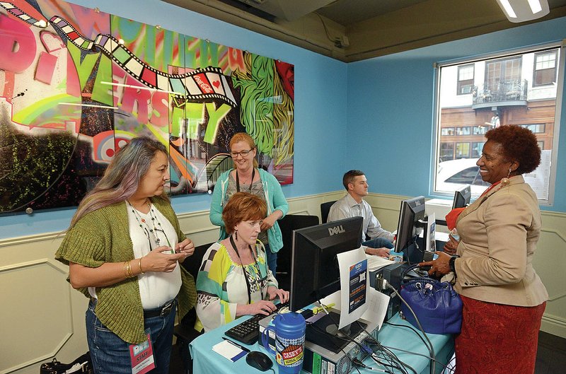 Cynthia Cooper (right) of Bentonville buys tickets Monday to a few panel discussions and film screenings at the Bentonville Film Festival box office in downtown Bentonville.