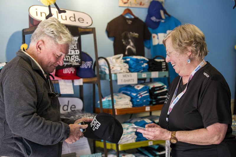 Volunteer Wendy Teach of Bentonville talks Tuesday with Charles Munro of Cape Coral, Fla., in the merchandise area in the Bentonville Film Festival office in downtown Bentonville.