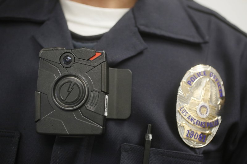 A Los Angeles police officer wears a body camera during a demonstration in Los Angeles in this photo from January 2014. Boston police had promised to launch a pilot program to outfi t officers with body cameras by April 2016 but now are saying it will be closer to June.