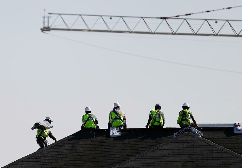 Construction workers rest on a rooftop in Atlanta after unloading packages of shingles from a hoisted pallet in this March photo. Worker productivity fell at an annual rate of 1 percent in the January-March period, the Labor Department said Wednesday. 