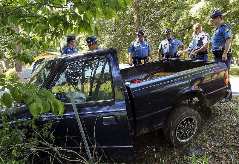 Arkansas State Police troopers examine a pickup they pursued Wednesday from Faulkner County to Maumelle.