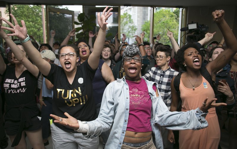 In this April 25, 2016 file photo, Krys Didtrey, left, and Gloria Merriweather, center, of Charlotte, N.C. lead the chants in opposition to the new North Carolina transgender law in the lobby of the State Legislative Building in Raleigh, N.C.