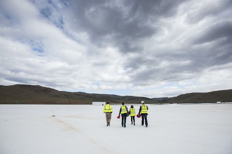 Reporters and Tesla employees walk on the roof of the Tesla Motors Inc. factory near Reno, Nev., on April 25. The huge battery factory is still under construction and scheduled to be producing battery cells by the end of the year.