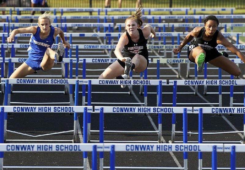 Lauren Holmes (right) helped lead Fayetteville to the Class 7A girls track and field title Thursday at Conway High School by winning individual titles in the 100-meter hurdles and the triple jump. Teammate McKenzie Penne (left) finished third in the hurdles. Bryant’s Deborah Shaw was second. Fayetteville also won the 7A boys title.