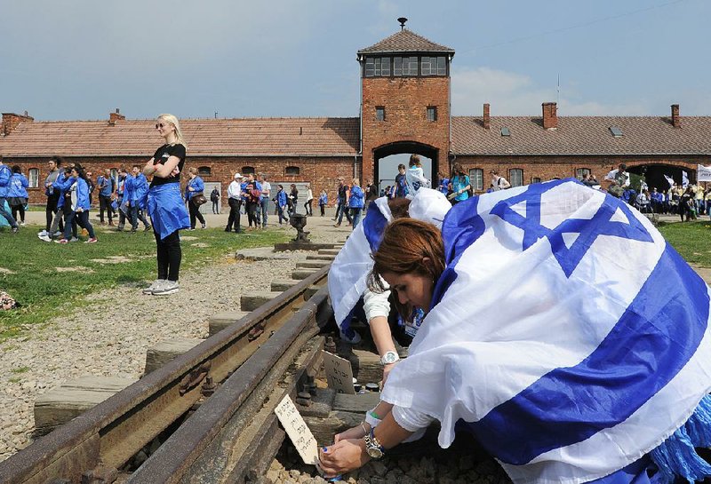 A girl places a plaque on the rail tracks at the former Nazi death camp Auschwitz-Birkenau during the yearly March of the Living on Thursday in Brzezinka, Poland.