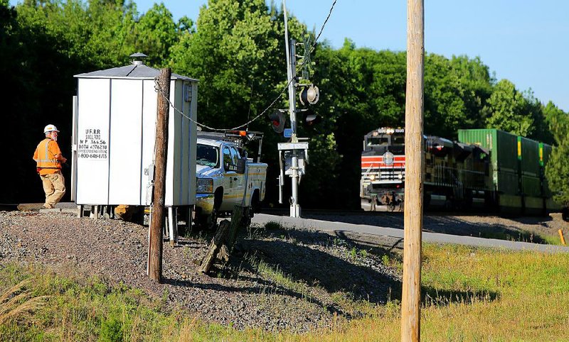 A Union Pacific worker (left) walks at the railroad crossing over Sidell Road near Benton Parkway where one person was killed and another injured in train-car collision early Friday. The train at the right was not involved in the accident. 