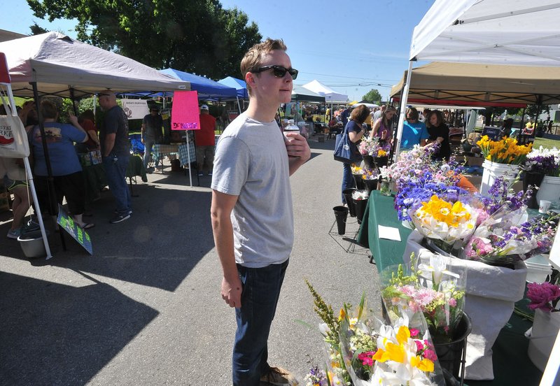 Payton Parker with the Springdale Planning Commission picks up a bouquet of flowers Saturday while visiting the Mill Street Market in Springdale.