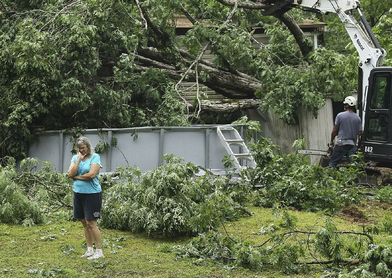 Yana Freeman is overcome with emotion Tuesday as workers remove fallen trees from her home at 1026 Sacred Path in Alexander after a tornado touched down on her Saline County property Monday night. The tornado was part of a storm system that pummeled parts of the state Monday night, producing straight-line winds in Fulton County that damaged property.