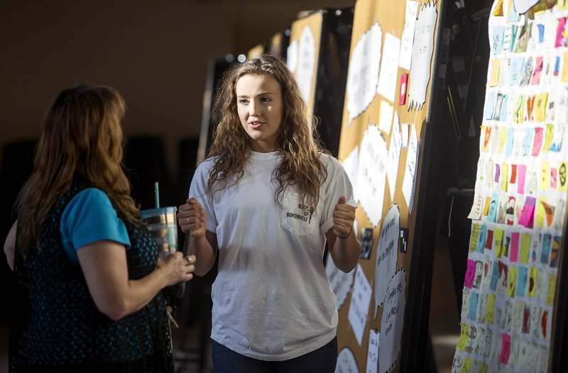 Isabel Neal (right), Bentonville High School junior, talks Tuesday with teacher Kim Carnahan during the launch party for the Voices Bentonville project at the school. Juniors have spent the majority of this semester crafting their personal memoirs, their stories of heartbreak, achievement, regret and love for the project.