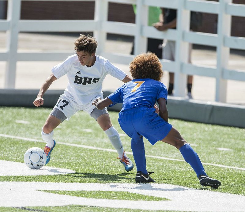 Bentonville’s Bruno Mariscotti (17) tries to maneuver past North Little Rock’s Teylen Patterson on Thursday during the Tigers’ 7-0 victory over the Charging Wildcats in the Class 7A state boys soccer tournament at Bulldog Stadium in Springdale.
