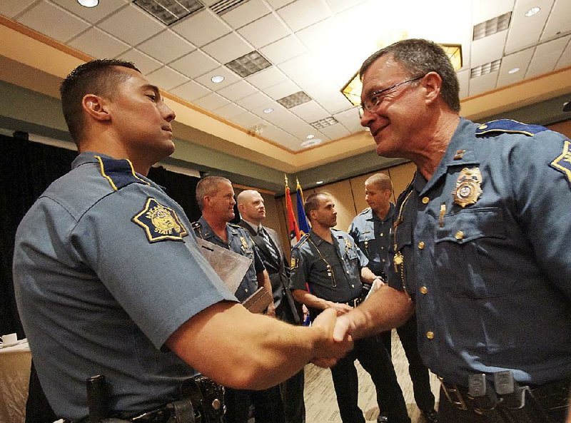 Trooper First Class Brandon Bennett (left) gets a congratulatory handshake Thursday from Capt. John Carter after being named Trooper of the Year during the annual Arkansas State Police awards luncheon in Little Rock. 