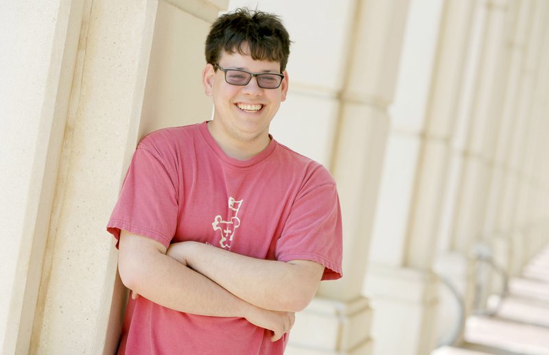 Andrew George, a member of the 2016 graduate class at the University of Arkansas, stands Wednesday in front of Mullins Library on the campus in Fayetteville. George is one of the first students in the Autism Support Program at the university to graduate. 