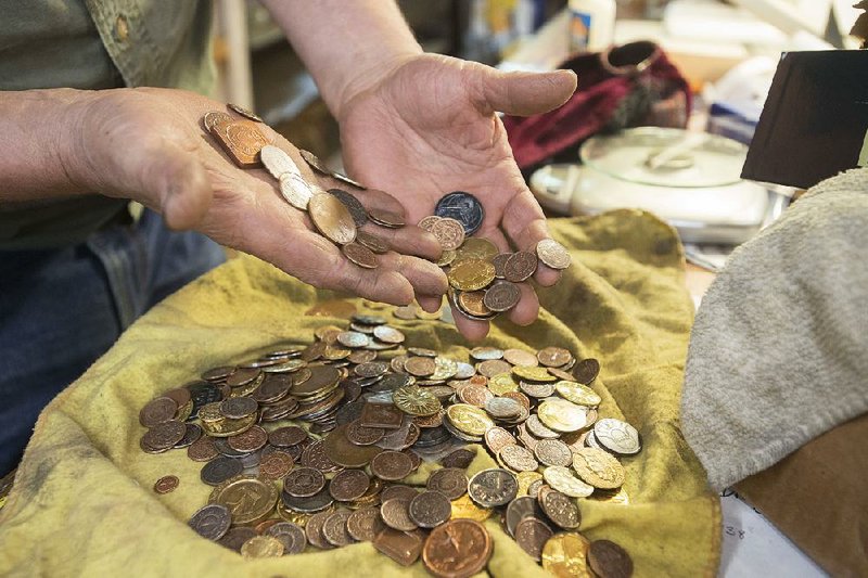 Tom Maringer runs his fingers through coins at his shop in Springdale. He makes collectible coins for several fantasy franchises, including Game of Thrones and The Lord of the Rings.