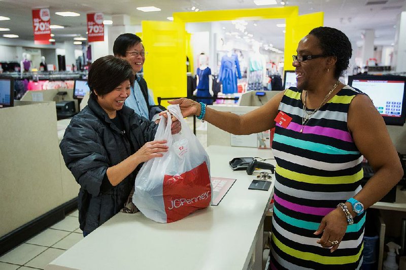 A J.C. Penney employee helps a customer at a store in the Queens Center Mall in New York in this file photo. The company on Friday reported a quarterly loss of $68 million.