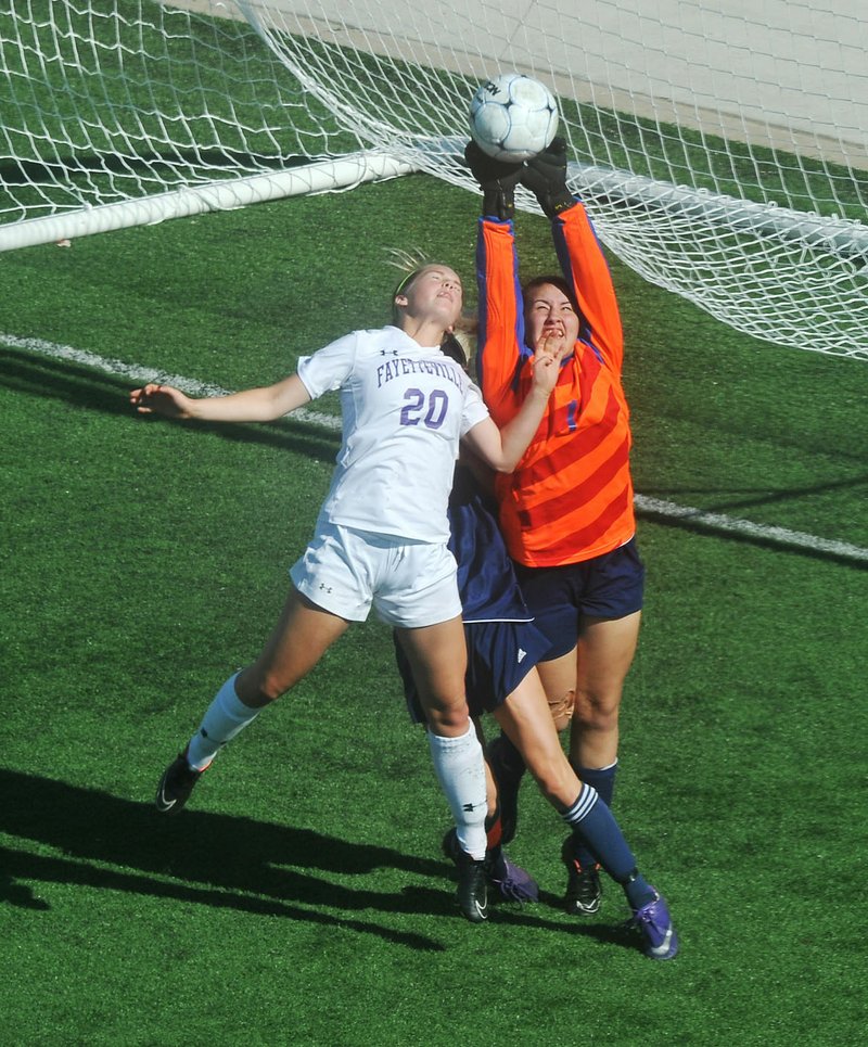 Rogers Heritage goalkeeper Micayla Fought (right) knocks away an entry pass before Fayetteville’s Myra Tubb can direct it toward the goal during Friday’s game at the Class 7A girls soccer tournament at Springdale Har-Ber High School. Fayetteville won 1-0. 