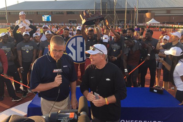 Arkansas men's track and field coach Chris Bucknam (right) speaks to ESPN's John Anderson as his team celebrates winning the SEC Outdoor Championship on Saturday, May 14, 2016, in Tuscaloosa, Ala.