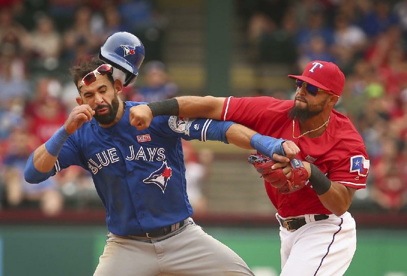 Texas second baseman Rougned Odor (right) lands a right to the face of Toronto outfi elder Jose Bautista during an eighth-inning altercation in Sunday’s game. The brawl began when Bautista slid through second base, which forced Odor to make an errant throw to fi rst base. Odor almost immediately shoved Bautista before connecting
with a punch. There were eight ejections in the game, which was the fi nal regular-season meeting between the teams. The Rangers held on to beat the Blue Jays 7-6.