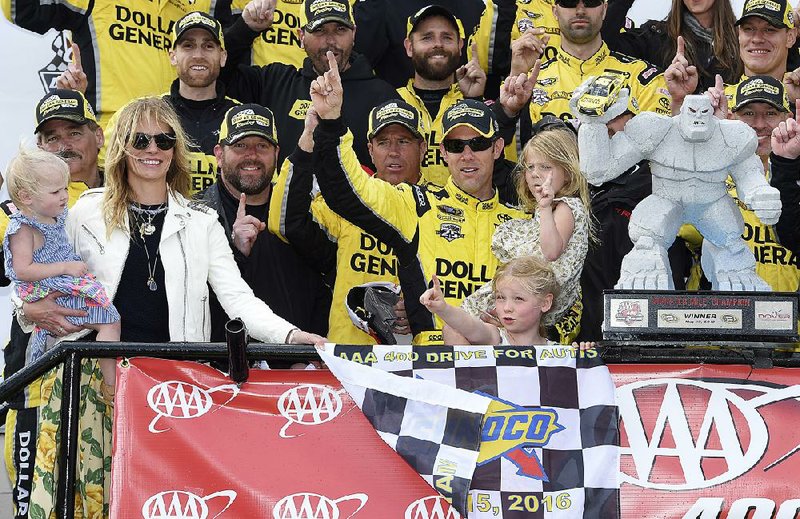 Matt Kenseth, center, poses with the trophy along with his wife Katie, left, and their three daughters after the NASCAR Sprint Cup series auto race, Sunday, May 15, 2016, at Dover International Speedway in Dover, Del.
