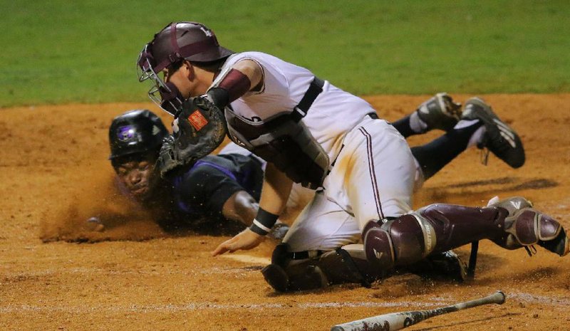 Chris Townsend of Central Arkansas slides safely into home plate ahead of a tag by UALR catcher Cameron Knight to score the game-winning run in the Bears’ 7-6 victory over the Trojans on Tuesday at Dickey-Stephens Park in North Little Rock. For more photos, visit arkansasonline.com/galleries.