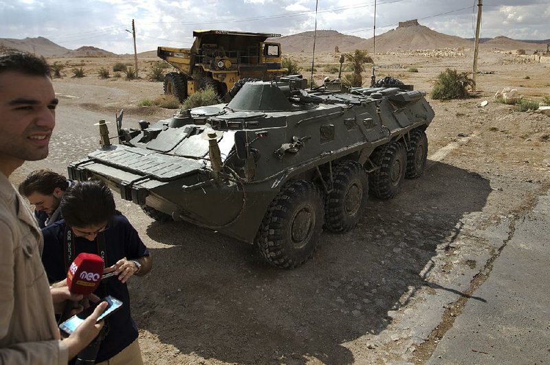 Journalists stand near Russian vehicles blocking a road leading to the ancient city of Palmyra, Syria, in this April photo. 