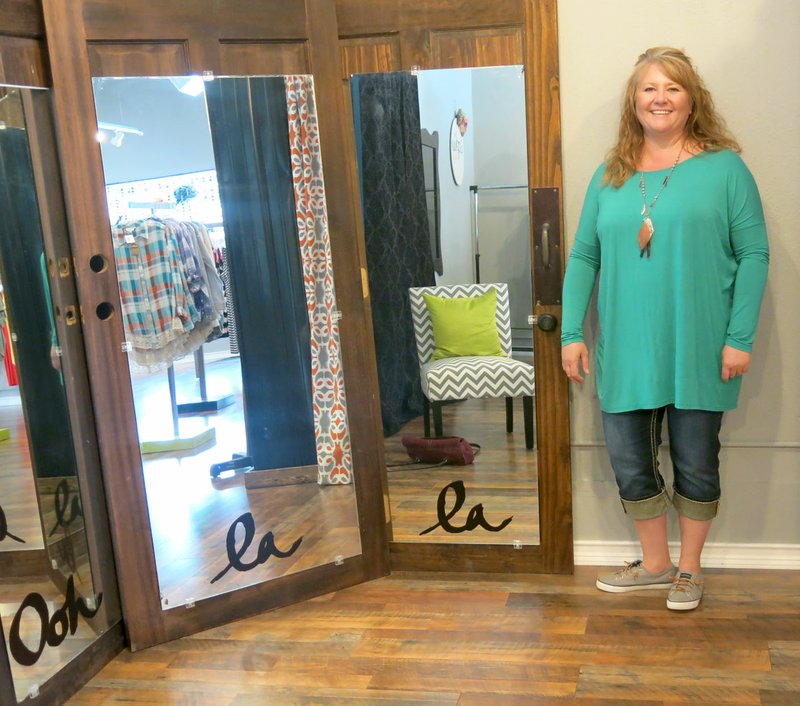 Photo by Susan Holland Tammie Loyd, owner of Sophie&#8217;s Boutique, poses beside the three-way mirror in the corner of her shop. These three wooden doors, discovered on an antique shopping trip with her sister, gave Loyd the inspiration for opening her business. The shop is now open on Main Street in Gravette, just west of the Gravette Public Library.