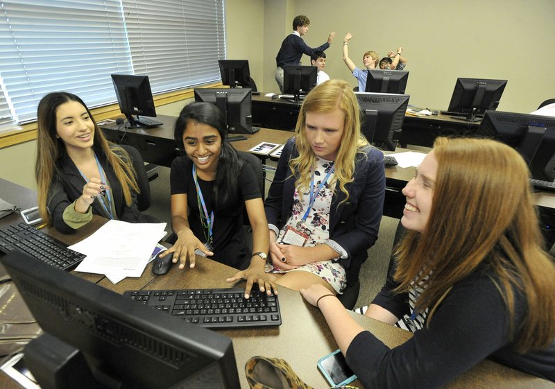 Rogers High School juniors Ariadna Valencia, (from left) Shreya Majagi, Sydney Figenska and Mary Treacy work on their project Tuesday during the annual Biz+Ed Student Competition at the Northwest Arkansas Community College’s Shewmaker Center for Global Business Development in Bentonville.