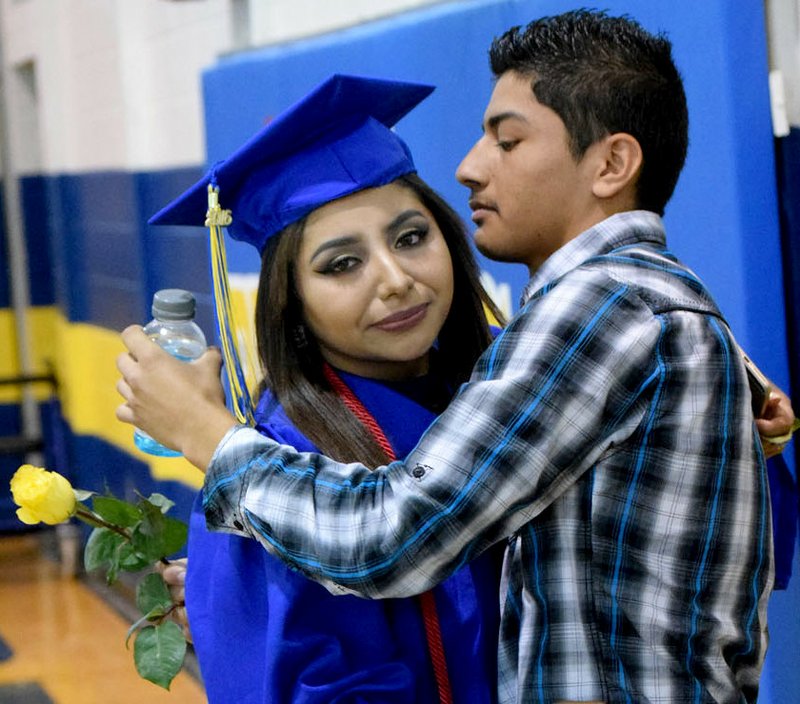 Photo by Mike Eckels Cindy Guadarrama (left) gives her brother Marck a rose and a hug just before receiving her diploma as part of the 2016 Decatur High School graduation ceremony in Peterson Gym May 15.