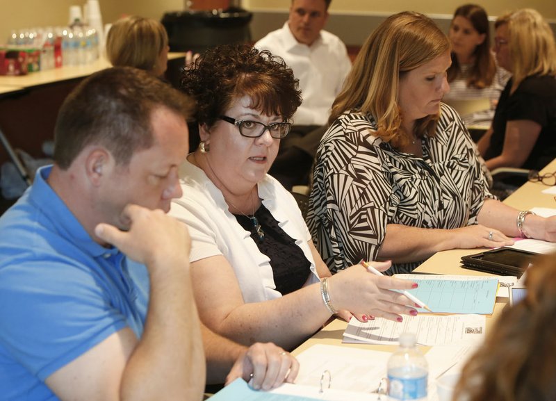 Ruth Mobley, a sixth grade teacher at Holt Middle School, discusses an action plan presentation Tuesday with her group at the Fayetteville Public Library. Ten action teams presented to a 30-member planning team for consideration in the plan. A draft is expected to be finished by June 1.