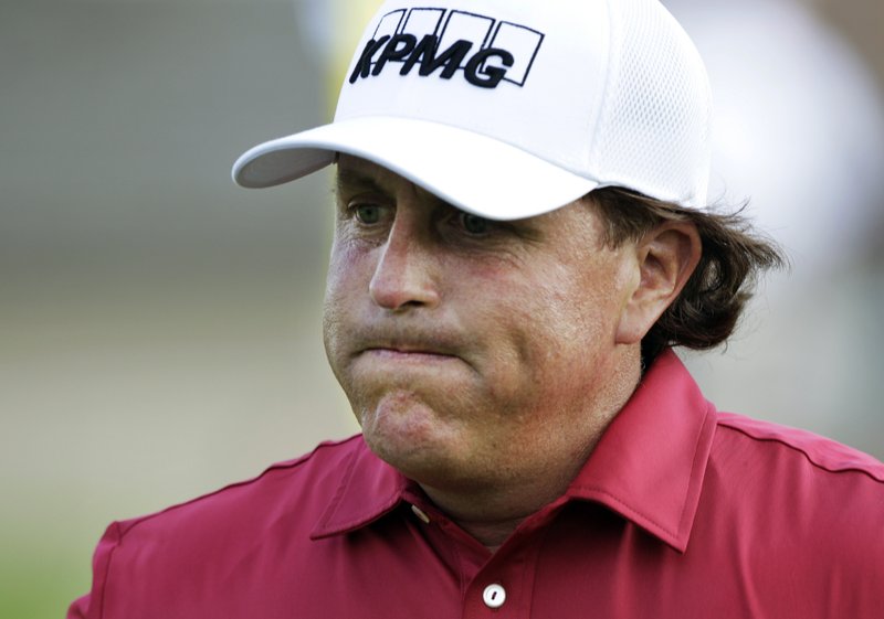 FILE - In this May 29, 2014, file photo, Phil Mickelson reacts after making double bogey on the 17th hole during the first round of the Memorial golf tournament in Dublin, Ohio. The Securities And Exchange Commission is filing a complaint against Mickelson related to insider trading. The SEC says in 2012, high-profile sports bettor Billy Walters called Mickelson, who owed him money, and urged him to trade Dean Foods stock. The SEC says Mickelson did so the next day and made a profit of $931,000. The SEC says Walters received tips and business information about Dean Foods Co. from former Dean Foods director Thomas Davis between 2008 and 2012. (AP Photo/Jay LaPrete, File)
