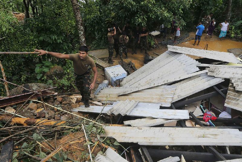 A Sri Lankan soldier walks over the debris of a house during a search of Elangapitiya village in central Sri Lanka on Thursday.