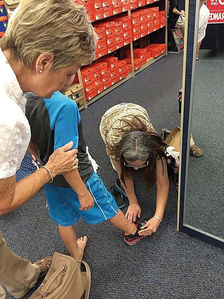Becky’s Kids shopping buddies Diane Davidson, left, and Karen Gist help a foster child try on new shoes during a back-to-school shopping trip.