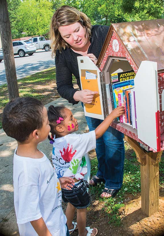 Jerusalem Greer, minister to children, youth and families at St. Peter’s Episcopal Church, helps Malachi Davis, 5, left, and his 4-year-old sister, Genesis Davis, take books from the St. Peter’s Little Free Library. They are the children of Brandi Davis and Guy Sykes and were in the neighborhood with their mother when they learned about the Little Free Library. The siblings are in preschool at the Community Action Program for Central Arkansas Head Start in Conway.