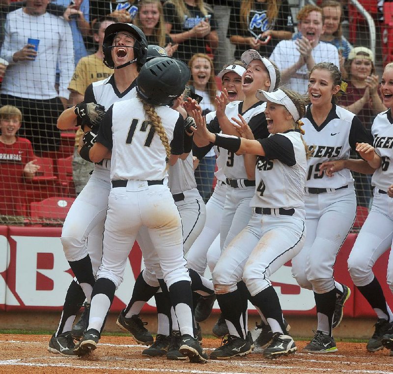 Keelah Griffith (far left) is grabbed by her Bentonville teammates after hitting a three-run home run in Class 7A state softball championship game against North Little Rock at Bogle Park in Fayetteville. The Lady Tigers beat the Lady Charging Wildcats 12-1.