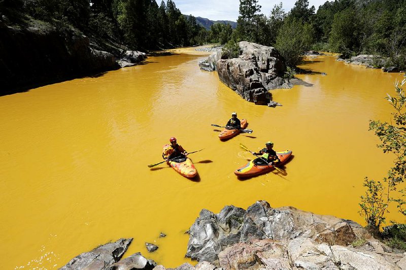 People kayak in August in the Animas River near Durango, Colo., floating in water colored from a mine waste spill.