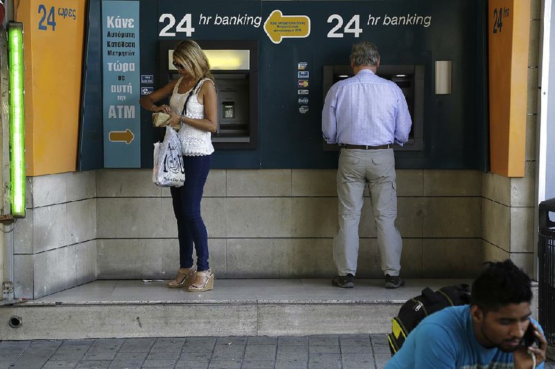 People use ATMs on Friday outside a bank in Nicosia, Cyprus. Harris Georgiades, Cyprus’ finance minister, said measures imposed three years ago during an economic crisis have “enabled the banking sector to heal to a large extent.”