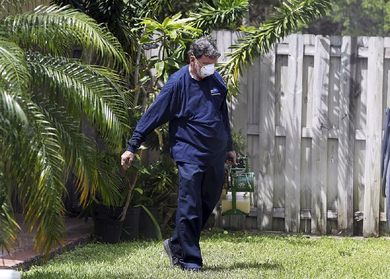 Giraldo Carratala, an inspector with the Miami-Dade County, Fla., mosquito control unit, sprays pesticide in the yard of a Miami home.