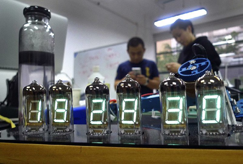 Eric Pan (left), founder of Seeed Technology, a contract manufacturer for “makers” — tinkerers, hackers and inventors — talks with a friend in April while a homemade digital clock is seen in the foreground in Shenzhen, China. 