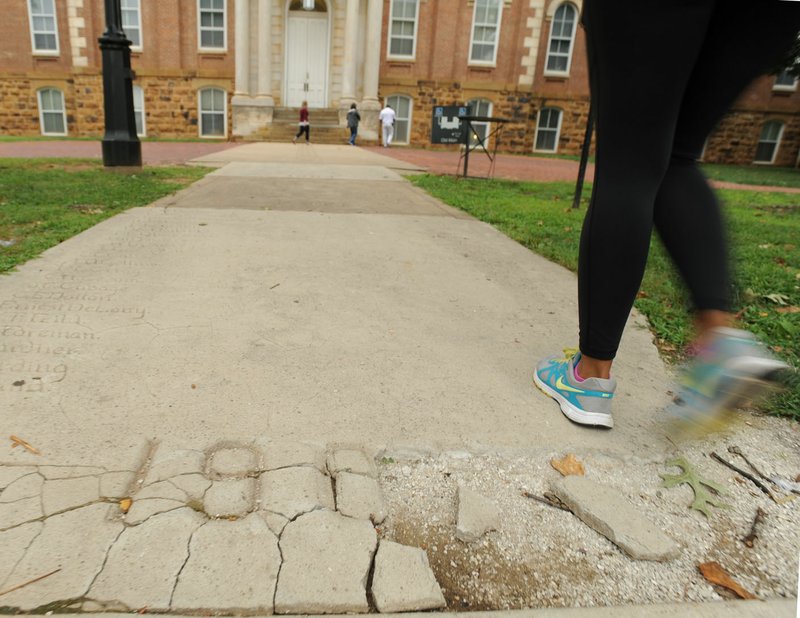 A student walks Aug. 21, 2015, past a damaged section of the 1906 portion of the Senior Walk on the east side