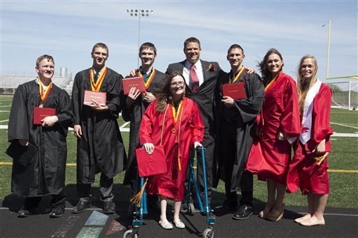 In this Sunday, May 22, 2016, photo, the McCaughey septuplets, the world's first surviving septuplets, from left, Nathan, Kenny Jr., Joel, Alexis, front, Principal Matthew Blackstone, Brandon, Kelsey and Natalie, pose for a picture after graduating from Carlisle High School, in Carlisle, Iowa. 