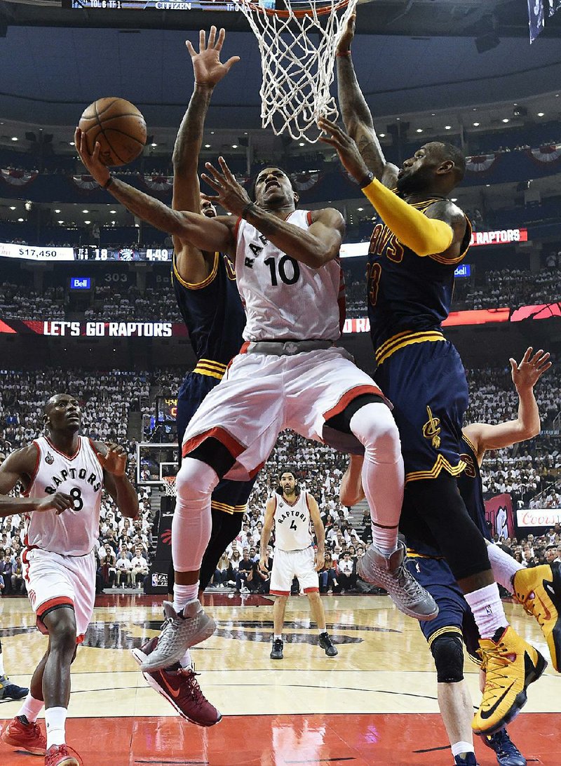 Toronto guard DeMar DeRozan (center) puts up a shot between Cleveland defenders J.R. Smith (left) and LeBron James during Game 4 of the NBA Eastern Conference final Monday. DeRozan scored 32 points as the Raptors beat the Cavaliers 105-99 to tie their series at 2-2.