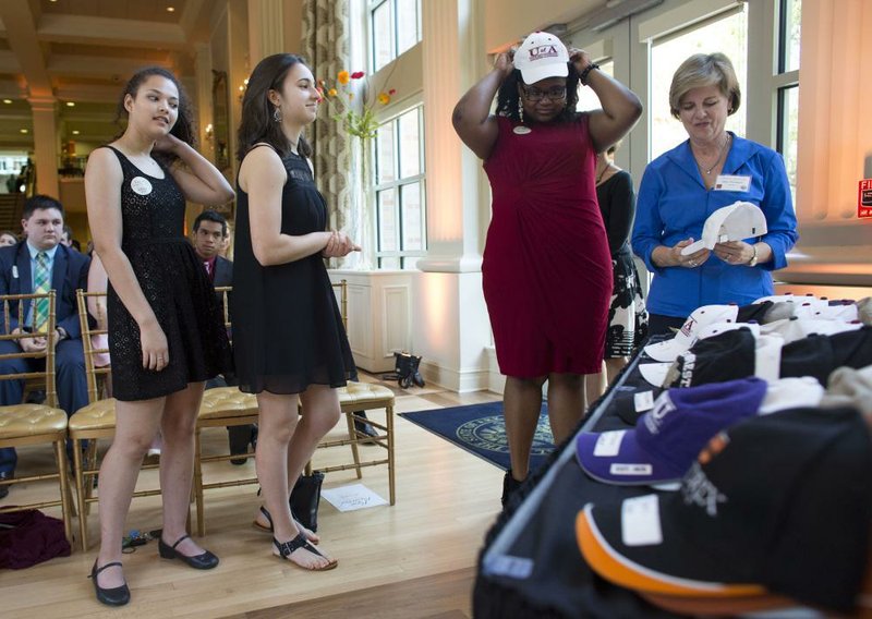 Little Rock School District seniors Chloe Berjot (from left) and Diana Basnakian wait Monday as Kerlisa Adams adjusts her cap before introducing herself to the crowd at the Governor’s Mansion in Little Rock during a ceremony to honor college-bound students. Adams plans to enroll at the University of Arkansas at Fayetteville.