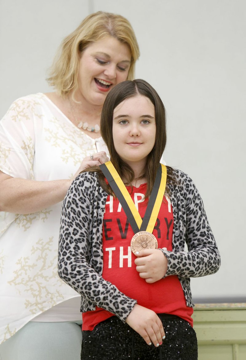 Gable Sloan, a fifth-grader at McNair Middle School, receives an engraved bronze medallion Monday to recognize her as a Distinguished Finalist for Arkansas in the 2016 Prudential Spirit of Community Awards from Principal Michelle Hayward at the school in Fayetteville. Gable has raised more than $2,300 selling her home-baked goods in a curbside bakery service she debuted in the summer.