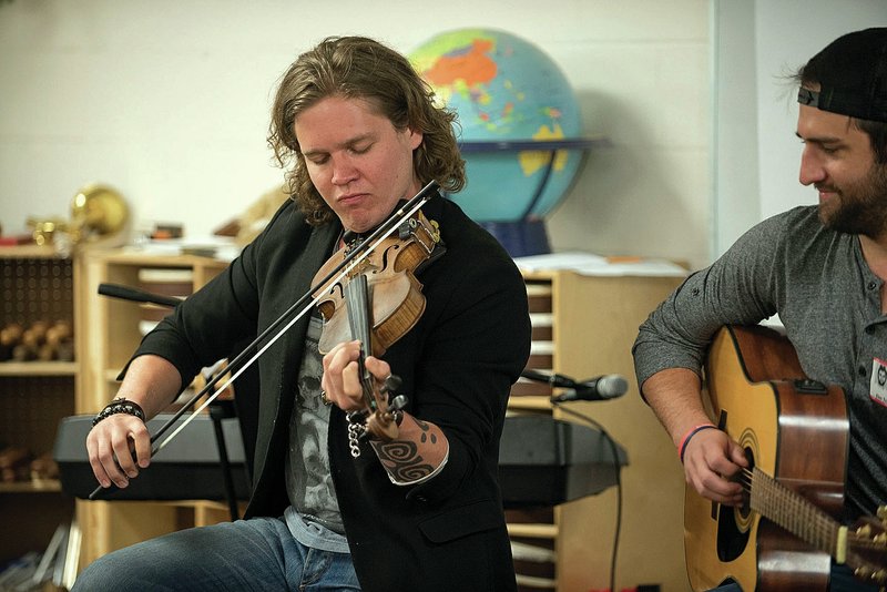 Elm Tree Elementary students learn Monday about Arkansas and music from Eric Dysart (left) and Josh Bryant of the music group Backroad Anthem. Students also got a visit from professional fisherman Greg Bohannan of Bentonville.