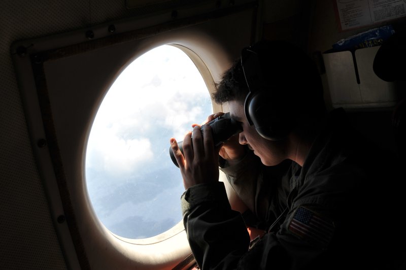 U.S. Navy LT. JG Dylon Porlas uses binoculars to look through the window of a U.S. Navy Lockheed P-3C Orion patrol aircraft from Sigonella, Sicily, Sunday, May 22, 2016, searching the area in the Mediterranean Sea where the Egyptair flight 804 en route from Paris to Cairo went missing on May 19. Search crews found floating human remains, luggage and seats from the doomed EgyptAir jetliner Friday but face a potentially more complex task in locating bigger pieces of wreckage and the black boxes vital to determining why the plane plunged into the Mediterranean. (AP Photo/Salvatore Cavalli)