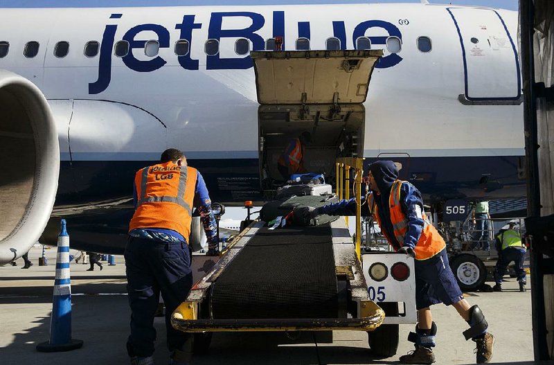 A ground crew unloads baggage from a JetBlue Airways Corp. jet at Long Beach Airport in Long Beach, Calif., in April. Airfares have fallen this year because of lower oil prices and airline moves to add seat capacity. 