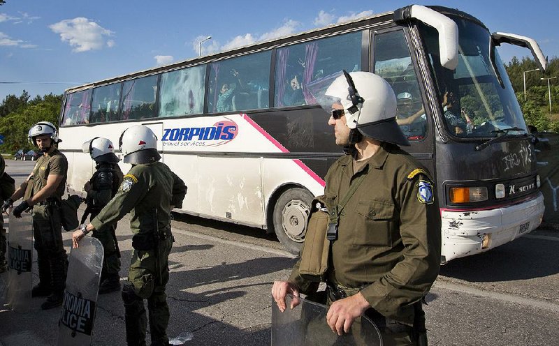 Greek police secure the passage of a bus carrying migrants evacuated from a makeshift camp in Idomeni, Greece, on Tuesday. 