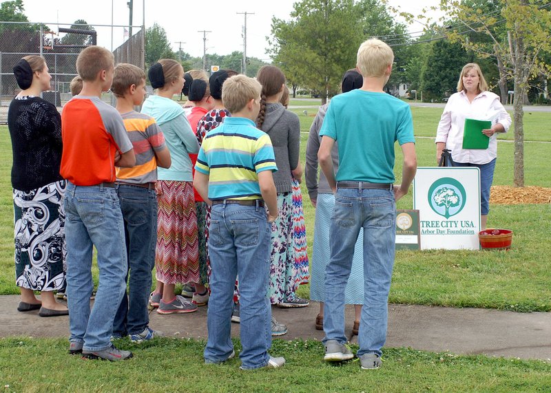 Photo by Randy Moll In a special observance on May 17, Gentry celebrated Arbor Day and the planting of four large red maple trees in the city park. Janie Parks, executive director of the Gentry Chamber of Commerce, explained to a group of students from Gentry Mennonite School the important role trees play in providing shade, cleaning the air and preventing soil erosion.