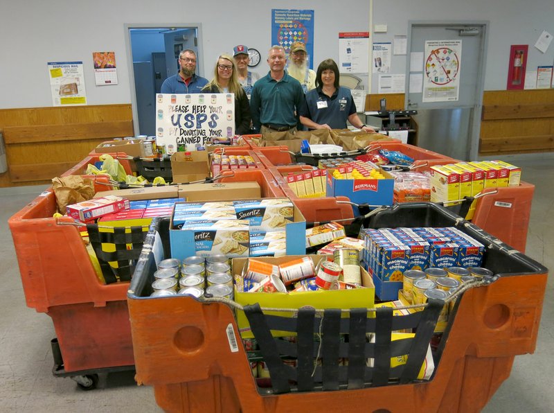 Photo by Susan Holland Employees of the Gravette Post Office posed behind the seven large carts of food they collected during the annual Stamp Out Hunger Food Drive. Postal customers, area businesses and individuals participated in the drive which brought in 2,066 pounds of food. Pictured are Paul Martin (front, left), and Erin Jackson, postal carriers; Gerald Garner, postmaster; Lorrie Amos, sales and service associate; Danny Boling (back, left), and Roy Ford, postal carriers.