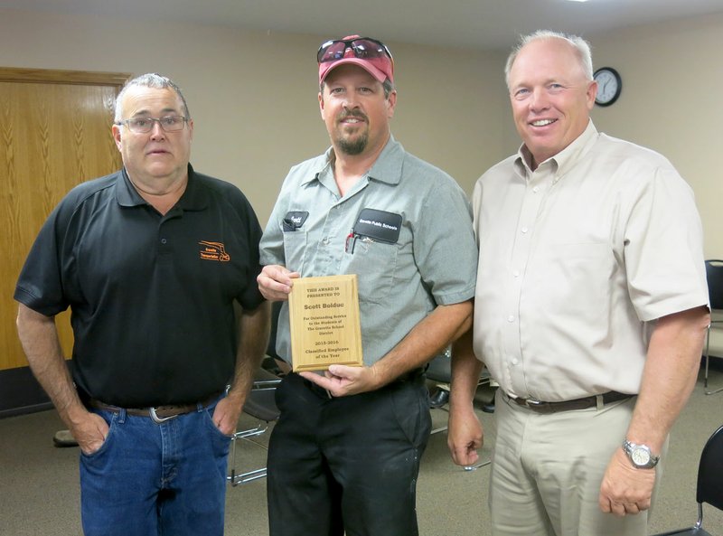 Photo by Susan Holland Scott Bolduc (center) displays the plaque he received at the May meeting of the Gravette School Board designating him as 2015-2016 classified employee of the year at Gravette Public Schools. He is pictured with Richard Carver, director of transportation and maintenance for the school system, and Jim Singleton, president of the school board.